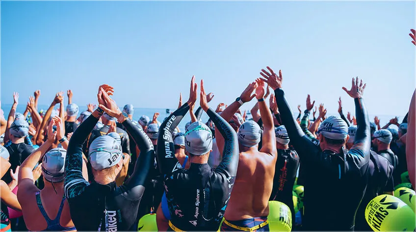Swimmers raising their arms at the start on the beach